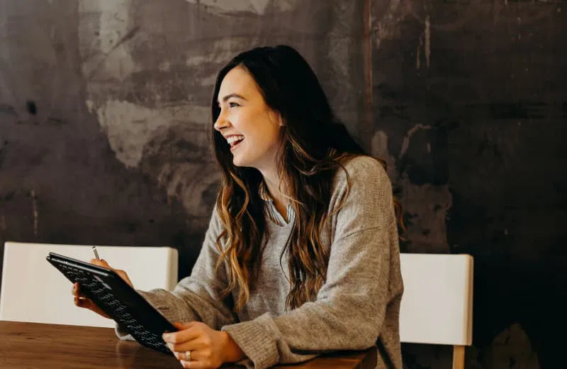 Femme riant en consultant son épargne sur sa tablette