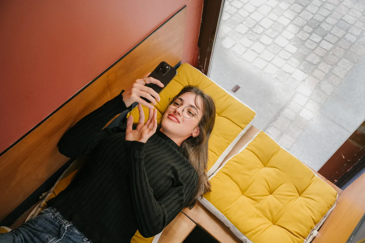 Femme sur son téléphone, allongée sur son canapé
