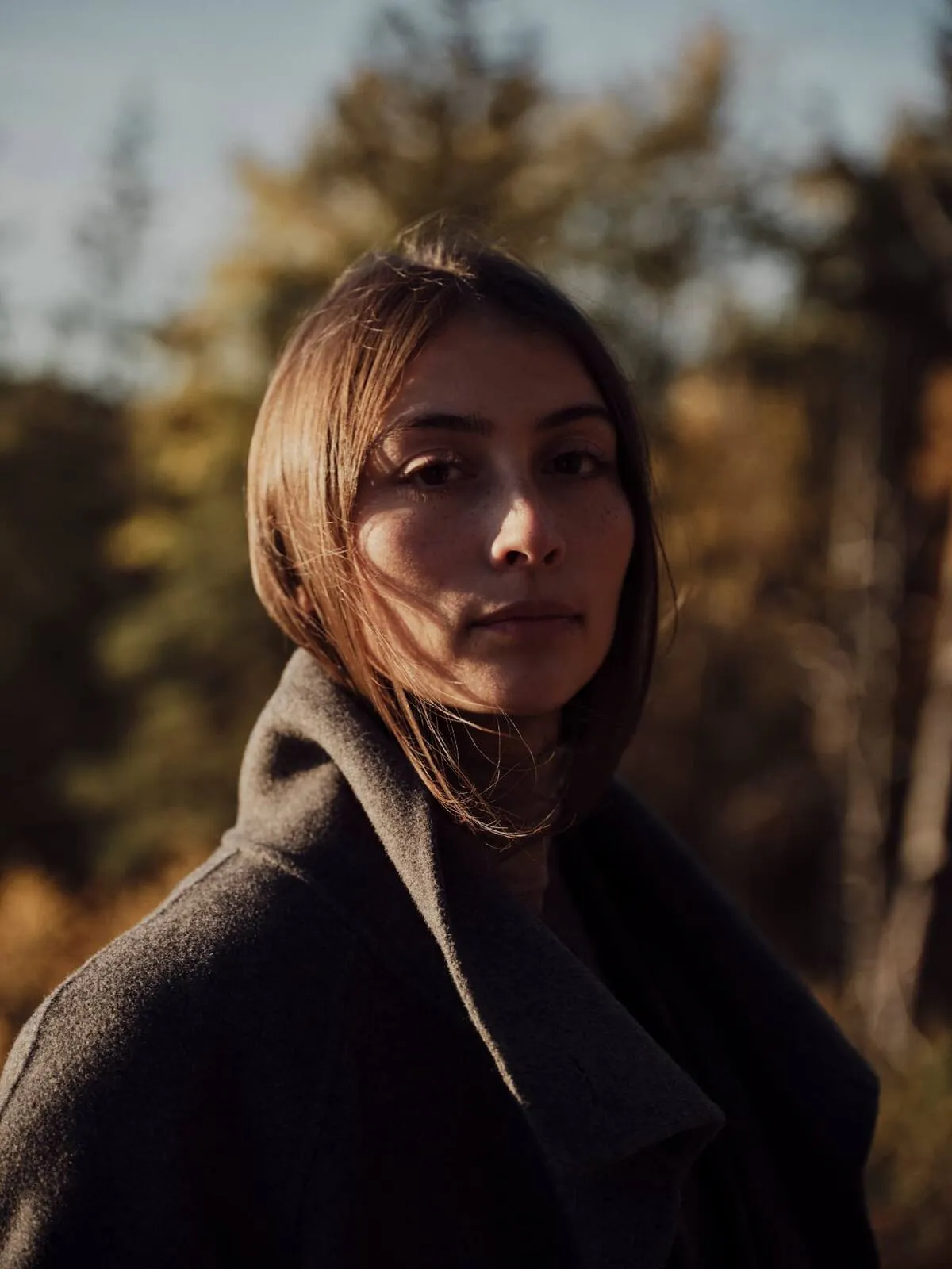 Portrait d'une femme en manteau sombre, dans une forêt d'automne